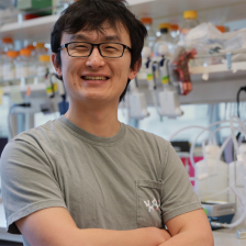 Bingxu Li, smiling and arms crossed, standing in a lab