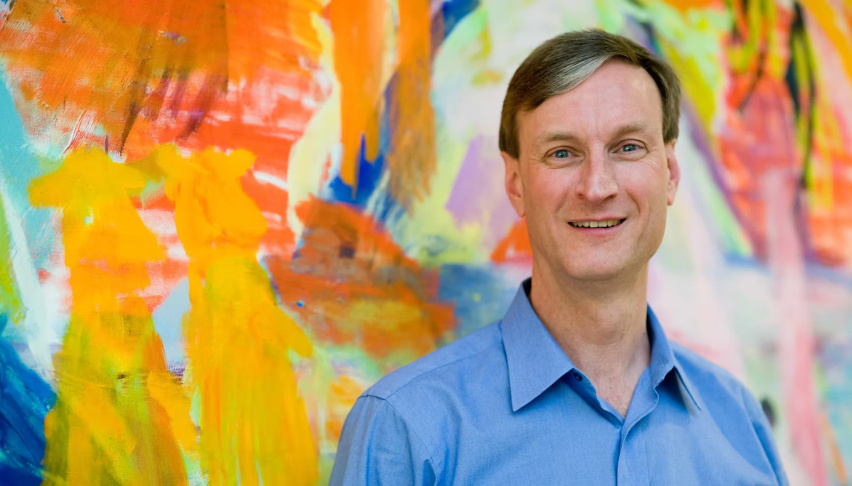 Man in front of brightly colored abstract painting