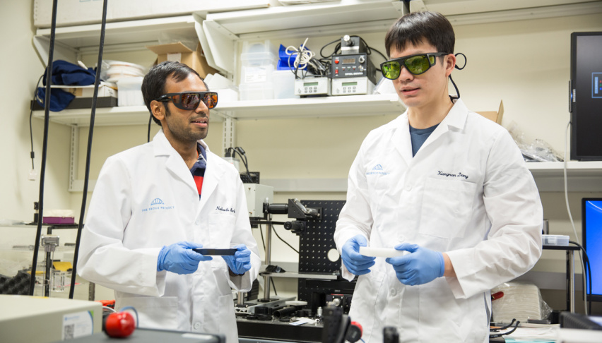 two researchers in protective glasses interact in a lab