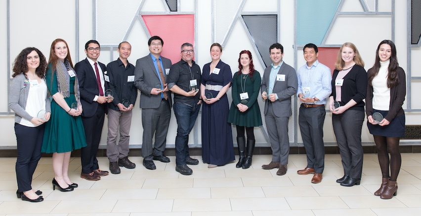 Twelve researchers holding trophies