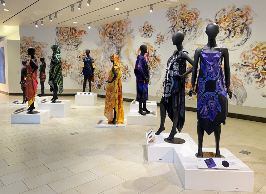 mannequins draped in colorful fabrics stand in an atrium