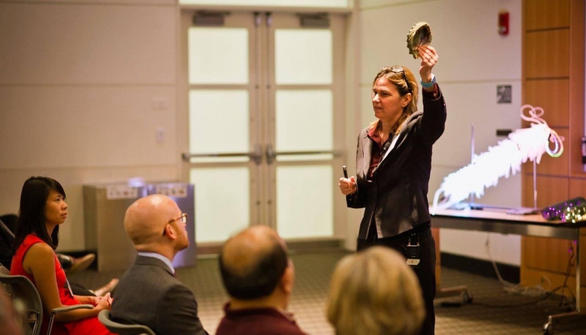 scientist holding up a seashell in front of an audience