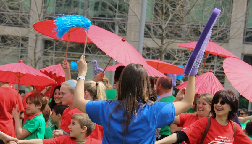 woman in blue shirt waves a purple foam finger at kids in red shirt