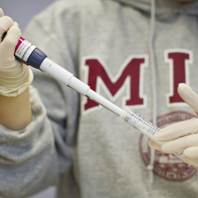scientist in an MIT sweatshirt pipetting