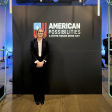 Ana Jacklenec stands in front of a wall with the "American Possibilities" logo