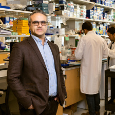 Omer Yilmaz in his lab. Two researchers work at a lab bench behind him.