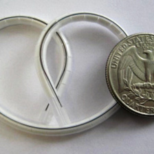 A plastic tube twisted into a pretzel shape about twice the width of the quarter next to it.