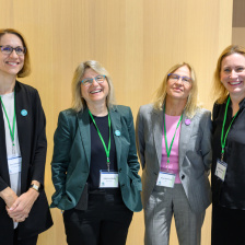 four women posing for a photo in a conference room