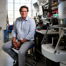 Photo of Giovanni Traverso, wearing a light blue shirt, sitting in his lab