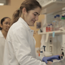 Two researchers wearing white lab coats working in a lab