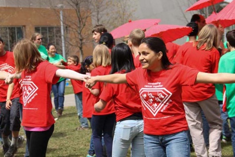 Young people in red shirts clasp hands in a circle