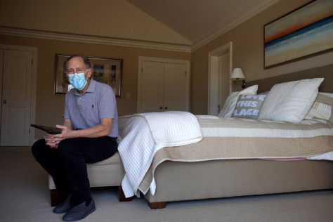 Langer wearing a face mask sitting on a bed