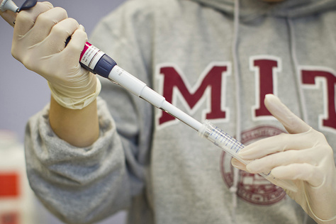 scientist in an MIT sweatshirt pipetting