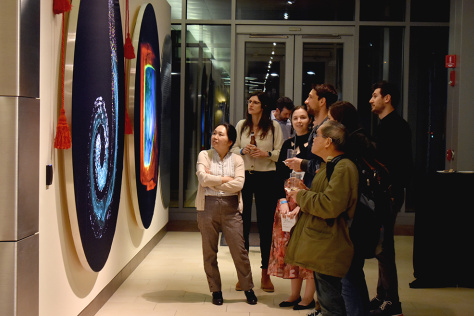 A group of people gathered around an image of a multilayered, square microparticle