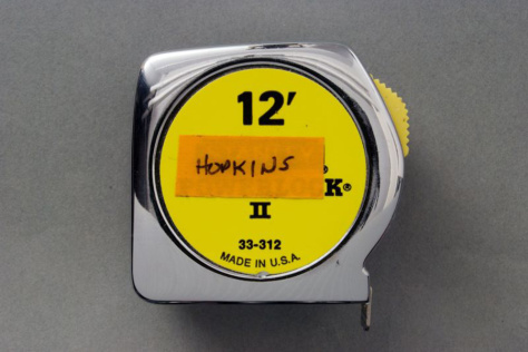 A standard 12 foot measuring tape with an orange label on it reading "Hopkins"