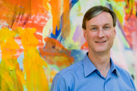 Man in front of brightly colored abstract painting