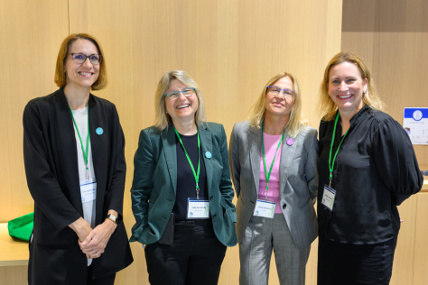 four women posing for a photo in a conference room