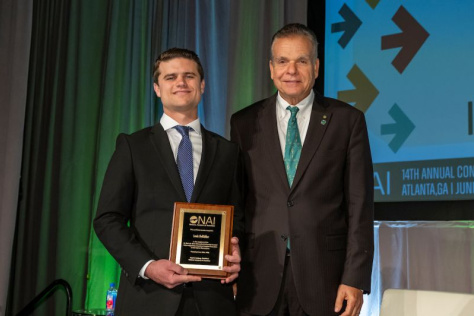 Two men standing next to each other holding an award