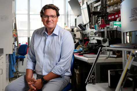Photo of Giovanni Traverso, wearing a light blue shirt, sitting in his lab