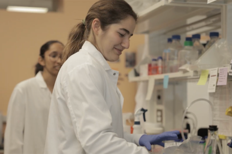 Two researchers wearing white lab coats working in a lab