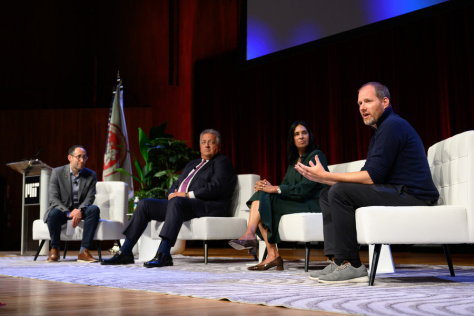 A group of people sitting on a stage during a panel discussion.