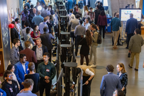 A group of people looking at poster presentations in an MIT building 