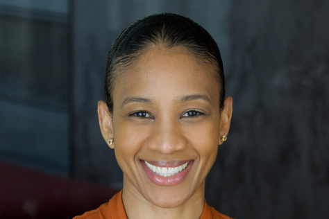 Photo of Whitney Henry, wearing an orange blouse and smiling for the camera