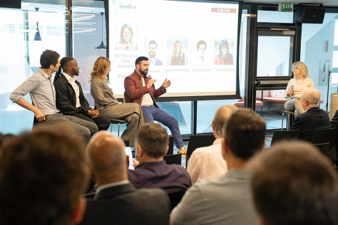 A group of people sitting on stage during a panel discussion 