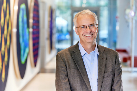Photo of Matthew Vander Heiden, standing in the Koch Institute gallery and smiling for the camera. 