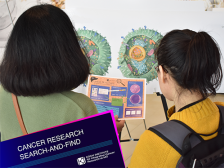 Two people, one wearing a backpack, comparing a colorful handout with a large illustration of tumors
