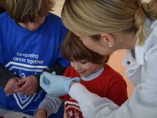 A researcher in a lab coat shows an object to two young visitors