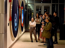 A group of people gazing at a large scale image of a microparticle