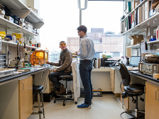 Two men converse at the far end of a lab bay