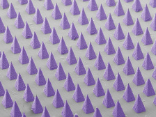 false-colored scanning electron micrograph of dozens of pyramid-shaped microneedles arranged in a grid